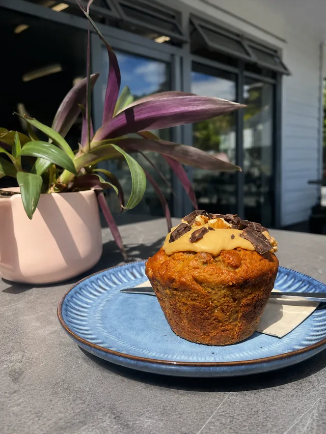 A frosted muffin on a blue plate beside a plant