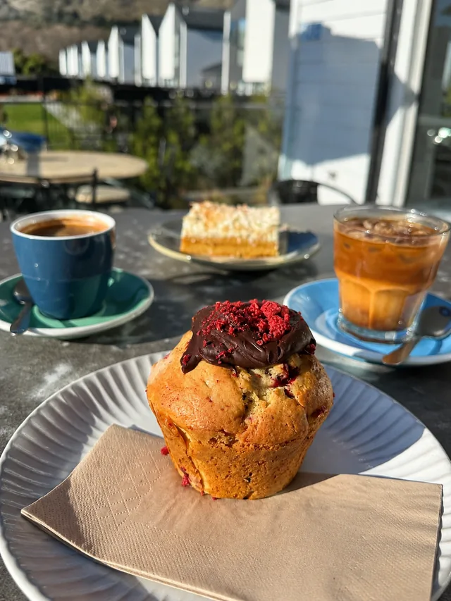A berry-topped muffin with coffee and iced drink
