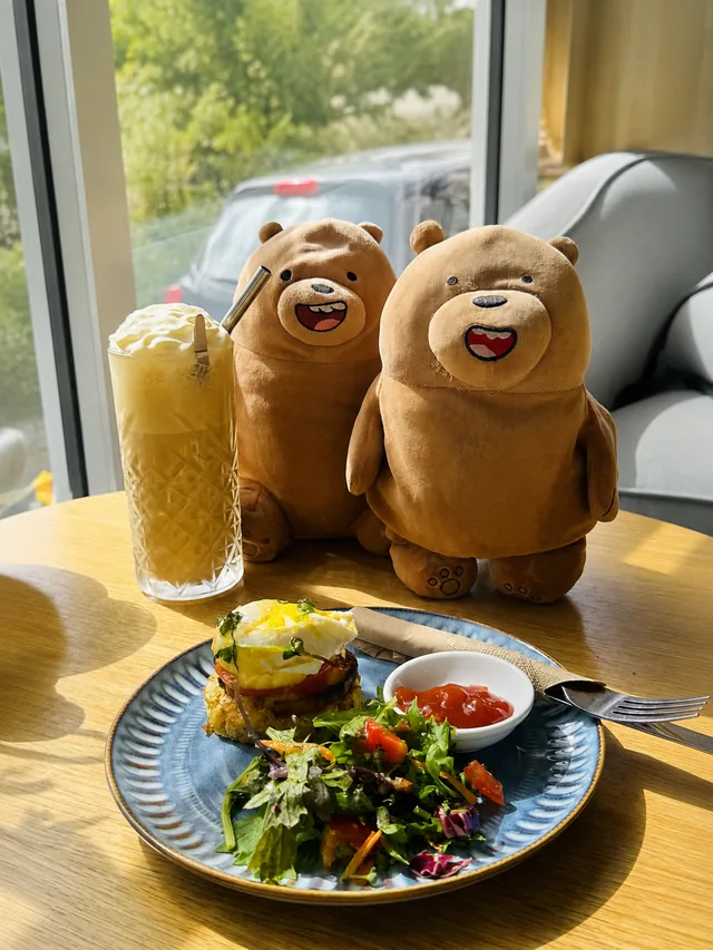 A sunny table with breakfast, a cold drink and two soft toy bears