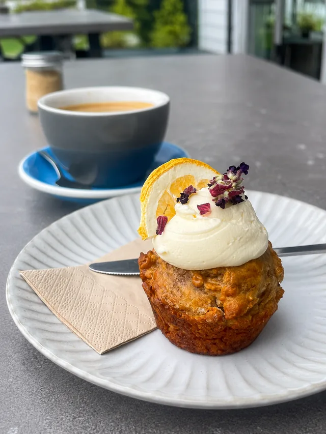 An iced muffin and coffee on an outdoor table